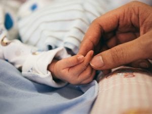 Parent holding newborn's hand