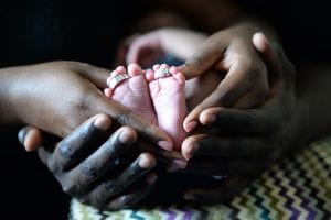 Couple holding baby's feet with wedding rings