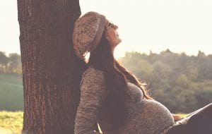 Pregnant woman sitting beneath a tree